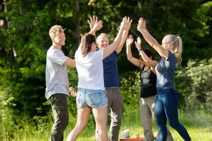 Glade mennesker laver teambuilding-øvelser udendørs.